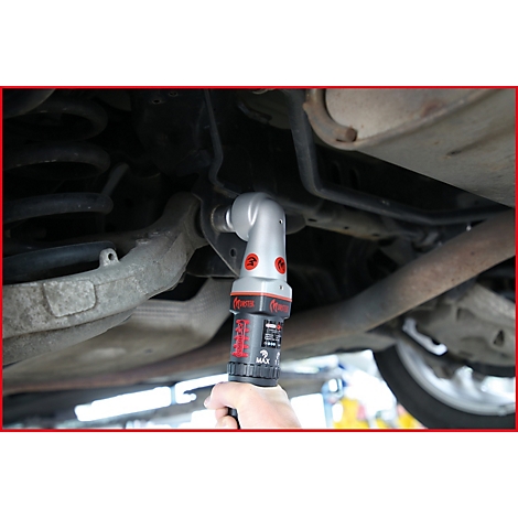 Hand hält einen silber-roten Winkelschrauber unter einem Auto.